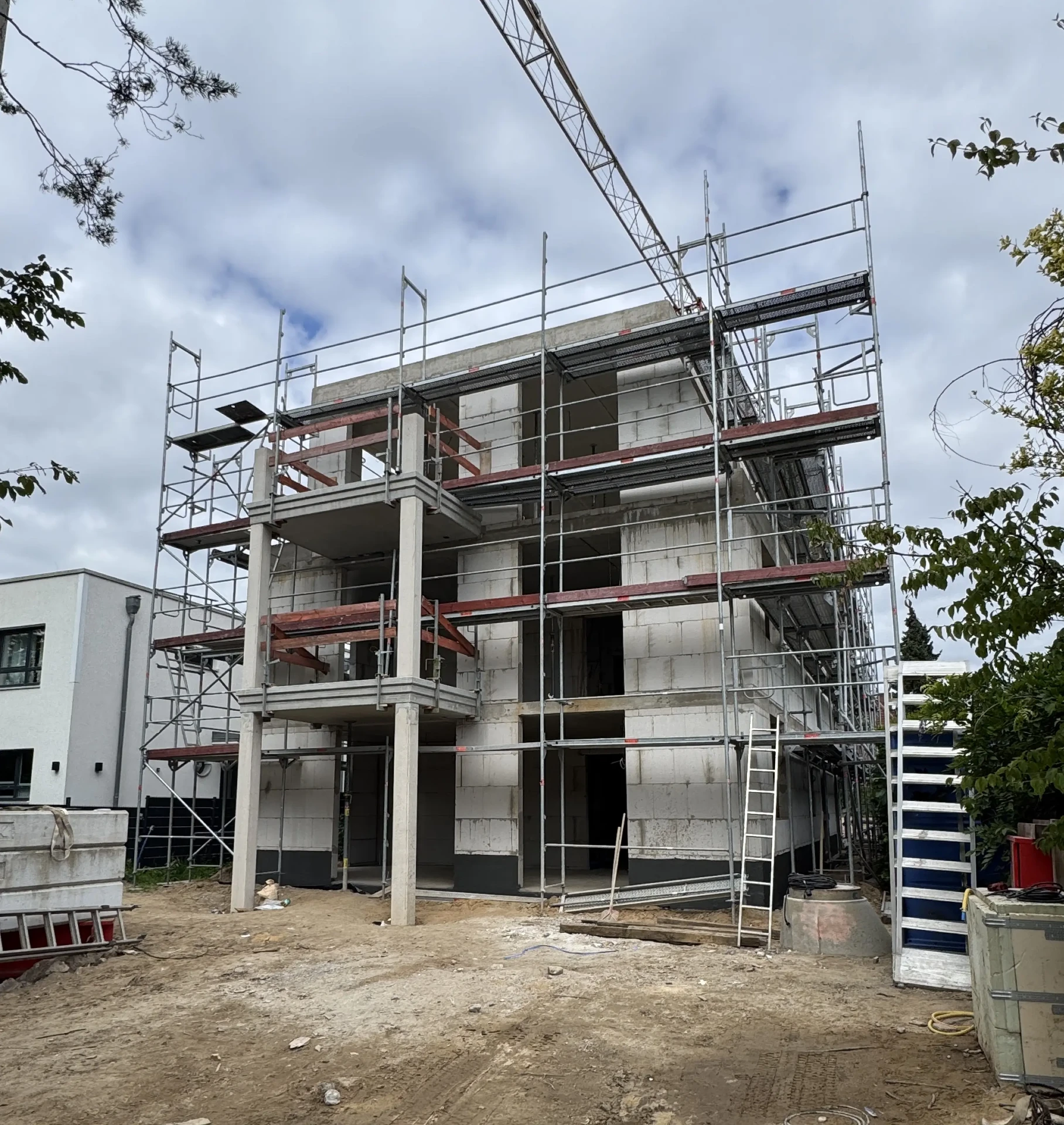 Rohbau der Villa Oberalster im August 2026 — Frontansicht mit Sichtbetonstützen und Gerüst